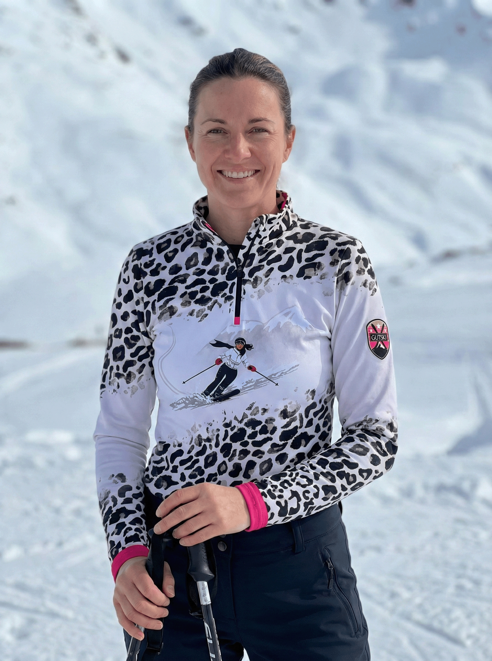 Vrouwelijk model draagt Gutski panterprint skipully in de sneeuw met roze accenten.